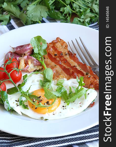 Fried egg with bacon rocket and cherry tomatoes. Fried egg with bacon rocket and cherry tomatoes