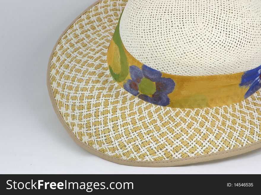 Straw hat with a ribbons of printed material around it. Straw hat with a ribbons of printed material around it