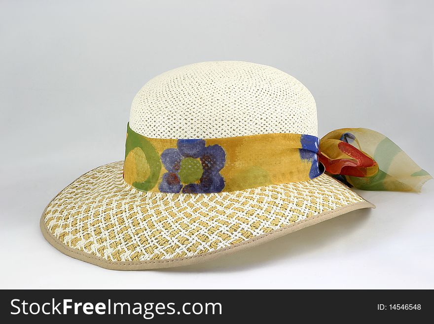 Straw hat with a ribbons of printed material around it. Straw hat with a ribbons of printed material around it