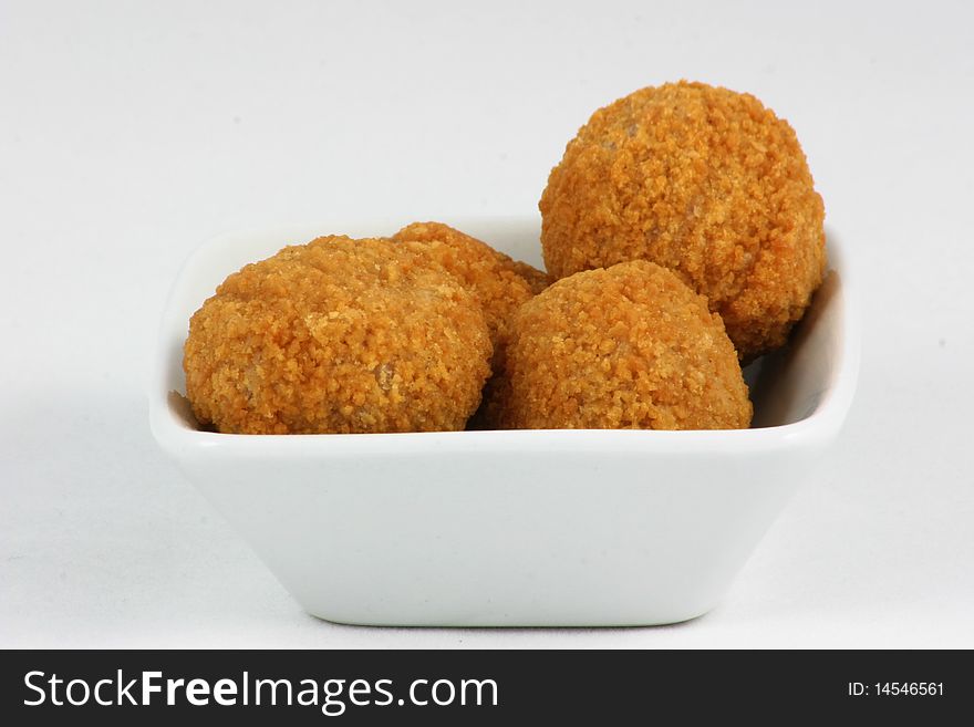 Small scotch eggs in a white ceramic dish. Small scotch eggs in a white ceramic dish