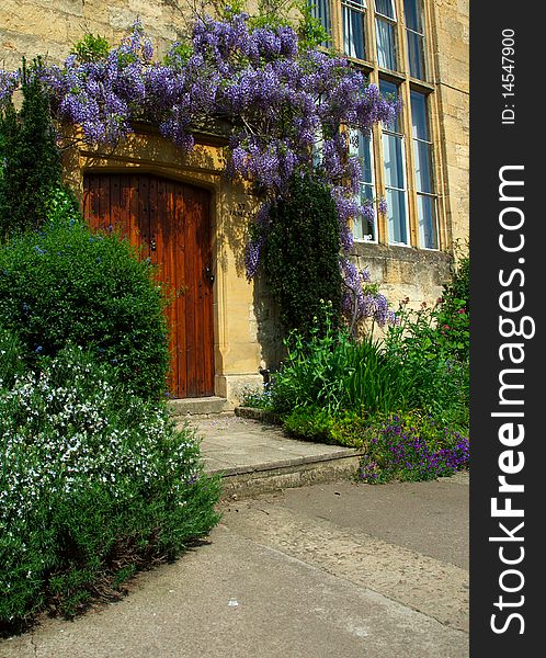 Flowers frame a door of one of the typical yellow limestone homes of the Cotswolds, Chipping Camden, England. Flowers frame a door of one of the typical yellow limestone homes of the Cotswolds, Chipping Camden, England