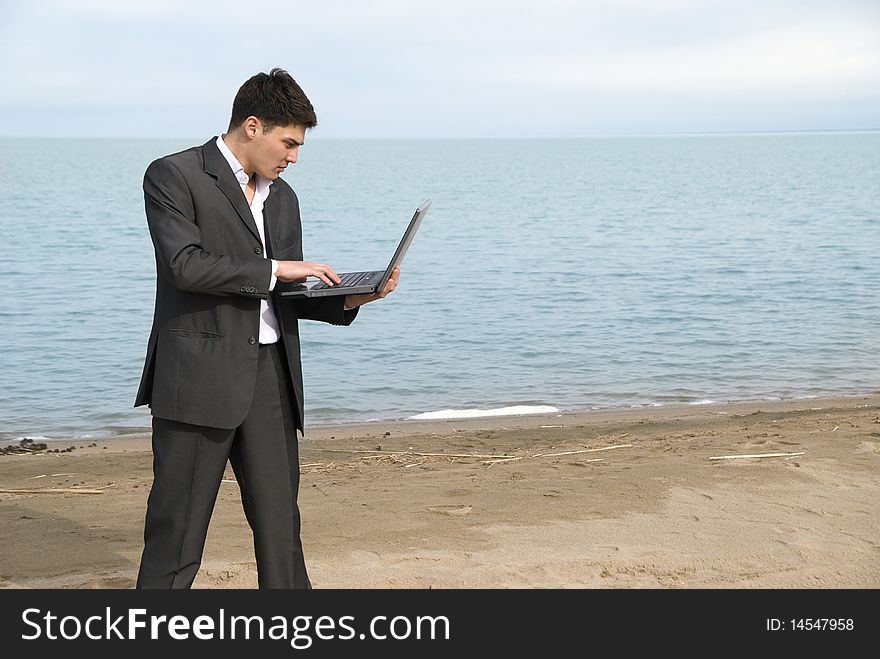 Young guy in a suit with a laptop on the beach. Young guy in a suit with a laptop on the beach
