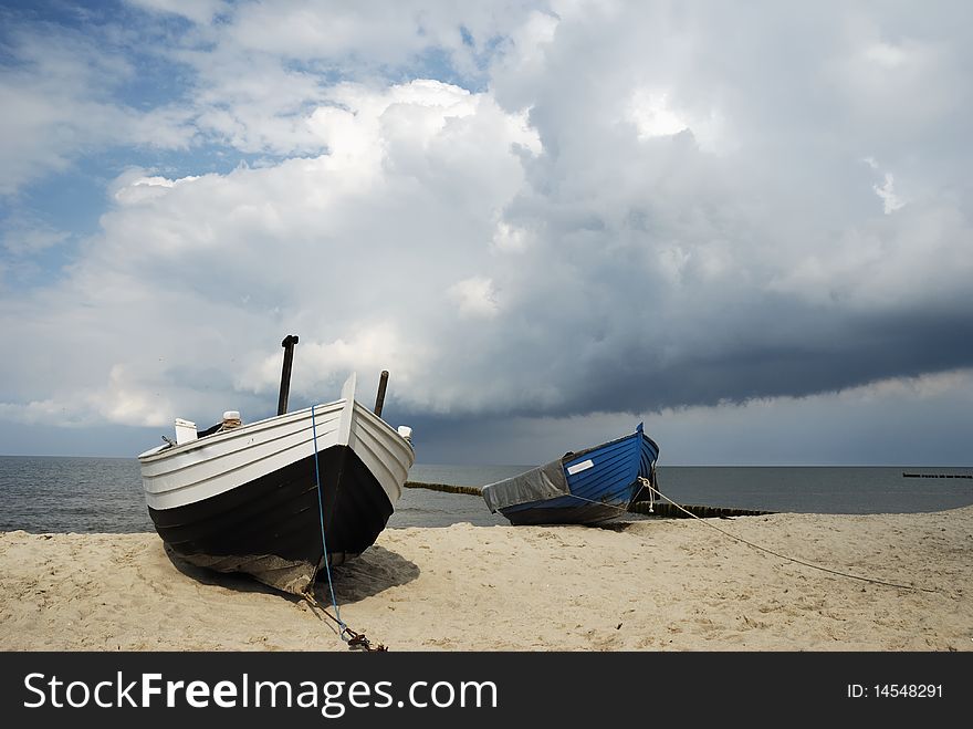 Two fishing boats on the beach after a rain shower.