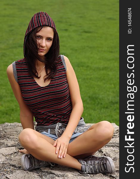 Casual teenager sitting on a rock outdoor