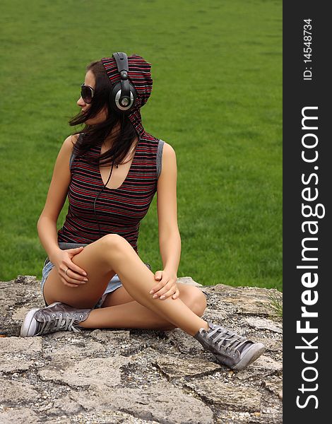 Casual teenager sitting on a rock listening to music. Casual teenager sitting on a rock listening to music