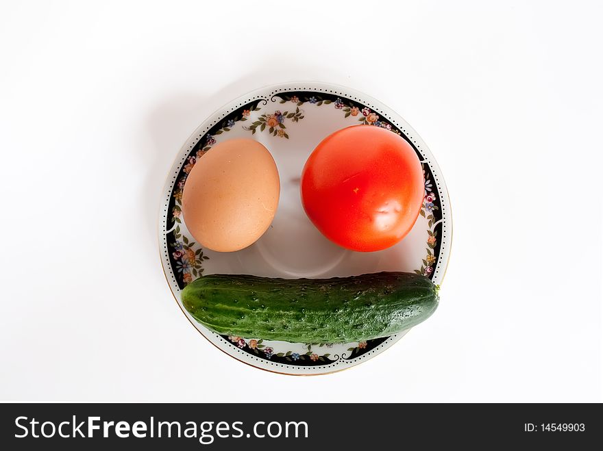 Egg, tomato and сucumber lie in the form of a smiling face. Egg, tomato and сucumber lie in the form of a smiling face