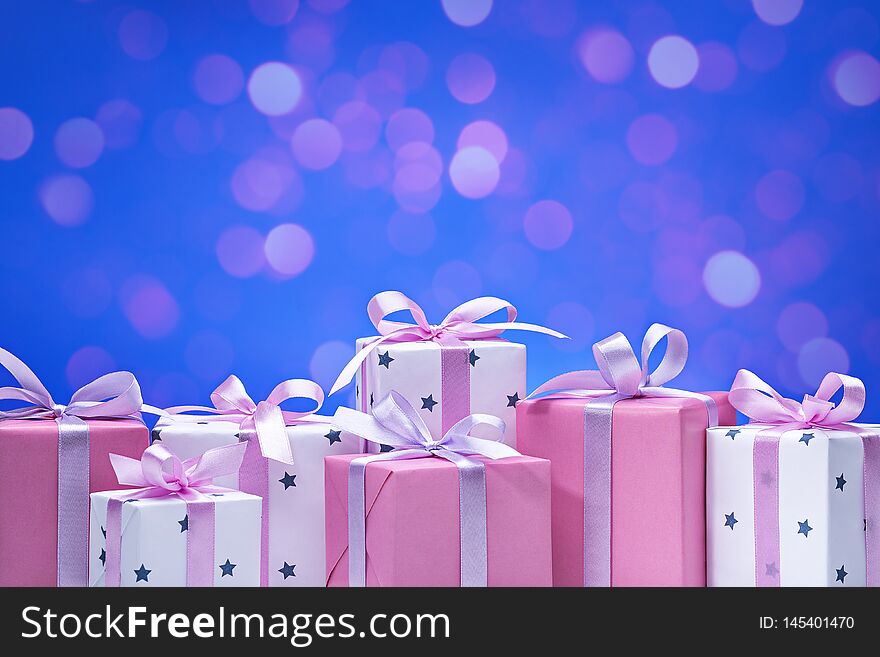 Â Gift boxes on bokeh background. Stylish modern gifts in pink and white paper, decorated with satin ribbon with bows. Copy space. Â Gift boxes on bokeh background. Stylish modern gifts in pink and white paper, decorated with satin ribbon with bows. Copy space.