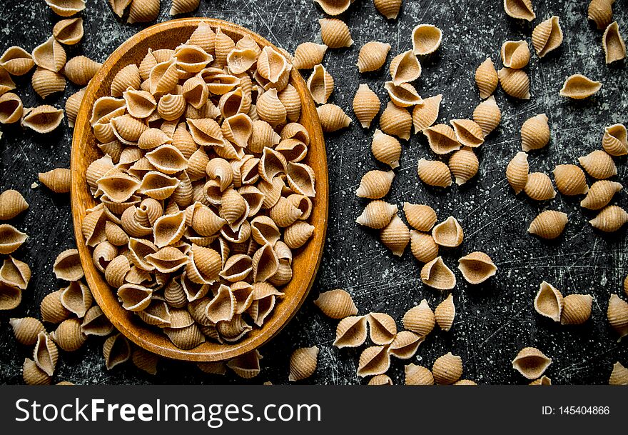 Pasta background. Dry pasta conchille in bowl. On rustic background