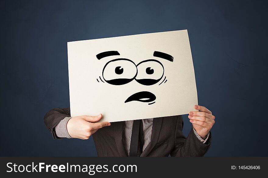 Person holding a paper with funny emoticon in front of her face