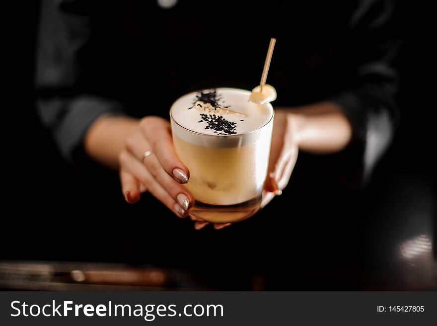 Close-up of a tasty alcohol cocktail with rosemary, sour mix and slice of ginger in female bartender`s hands. Close-up of a tasty alcohol cocktail with rosemary, sour mix and slice of ginger in female bartender`s hands