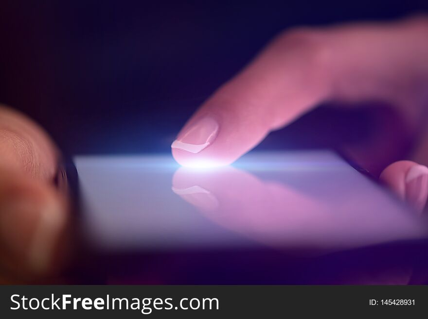 Finger touching phone with dark background