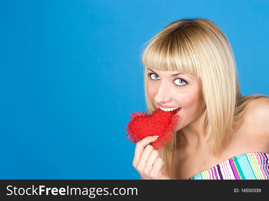 Attractive Woman Biting A Red Heart Over Blue