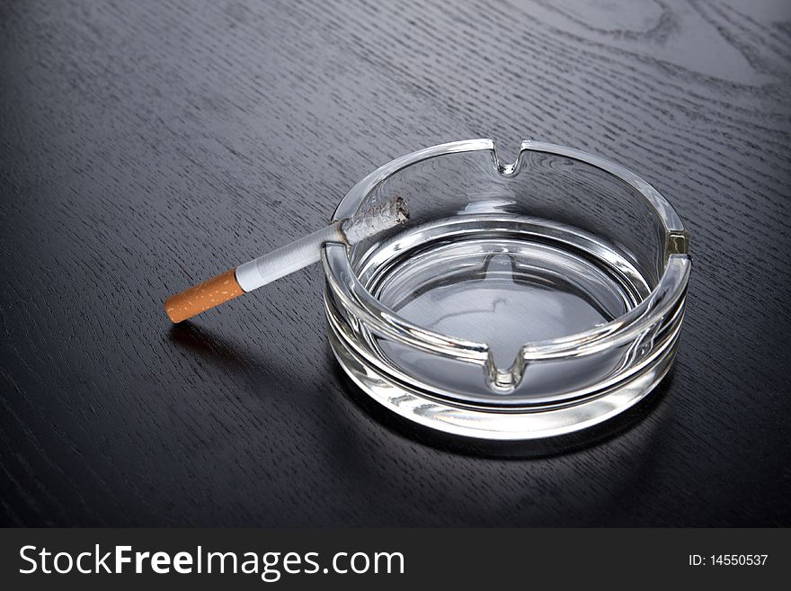 Cigarette and ashtray on black table