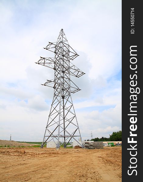 The high-voltage support standing on the earth, against the blue sky