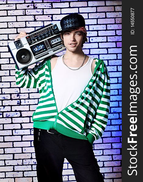 Trendy young man posing  against a brick wall with tape recorder. Trendy young man posing  against a brick wall with tape recorder.