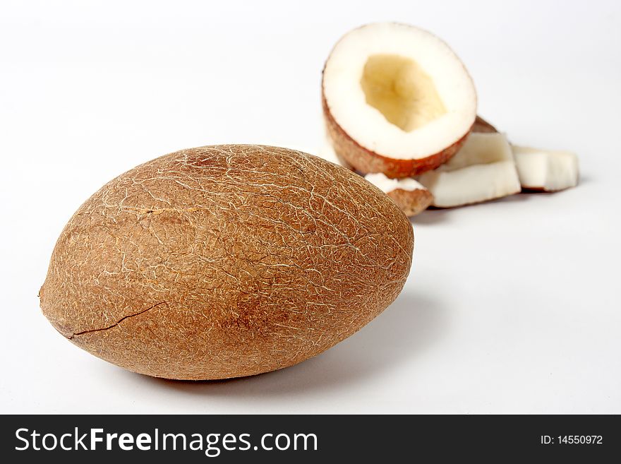 Unshelled coconut on white background with some pieces of nut