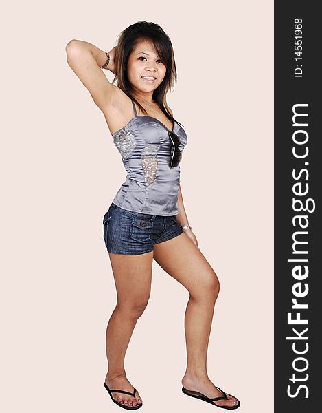 A young pretty Cambodian woman, standing in the studio in shorts and
a silver blouse and sandals, holding her hand on her hair, over beige. A young pretty Cambodian woman, standing in the studio in shorts and
a silver blouse and sandals, holding her hand on her hair, over beige.