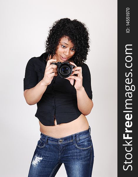 A pretty Hispanic woman looking at her new camera to find the right
setting for the next picture, in a black blouse and jeans, over light gray. A pretty Hispanic woman looking at her new camera to find the right
setting for the next picture, in a black blouse and jeans, over light gray.