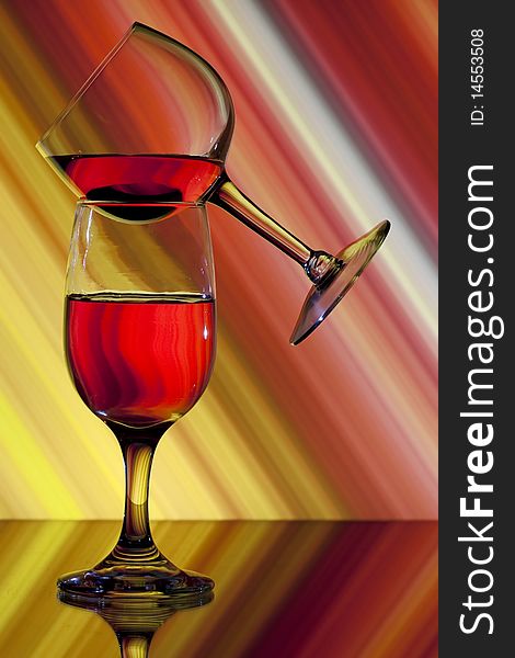 One wine glass balanced on another with colorful background. One wine glass balanced on another with colorful background