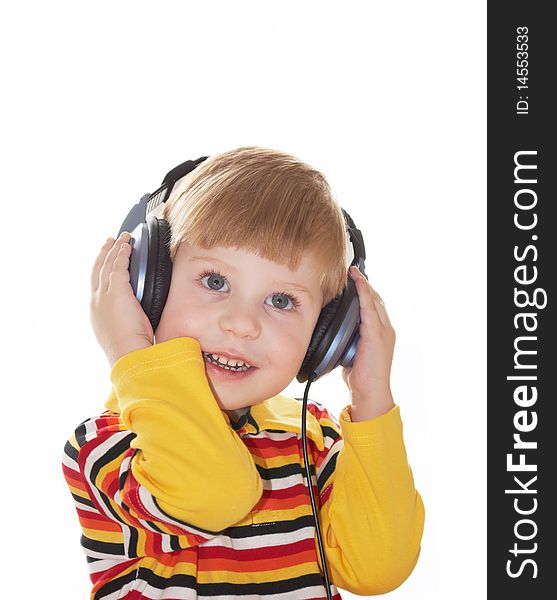 The little boy in headphones listens to music on a white background. The little boy in headphones listens to music on a white background