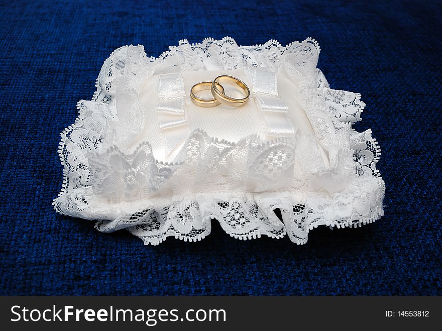 Gold wedding rings on a satiny pillow