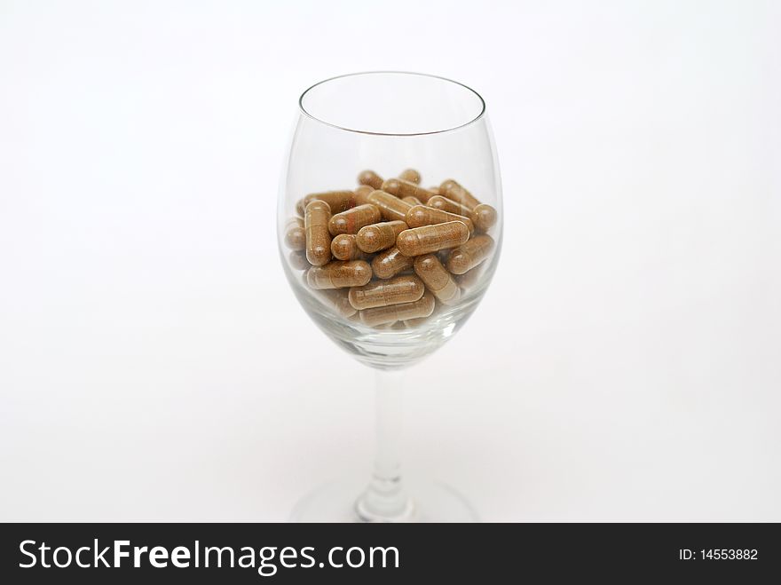 Medicine capsules in wine glass. For drug addiction, healthy eating and lifestyle, dieting and slimming, and healthcare concepts. Medicine capsules in wine glass. For drug addiction, healthy eating and lifestyle, dieting and slimming, and healthcare concepts.
