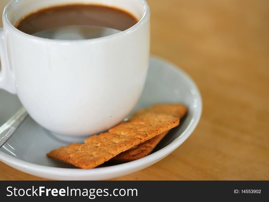 Coffee beverage in white cup and saucer with biscuits. For food and beverage, and diet and nutrition concepts. Coffee beverage in white cup and saucer with biscuits. For food and beverage, and diet and nutrition concepts.