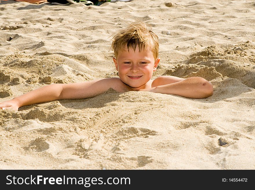 Child at the beach is covered by sand