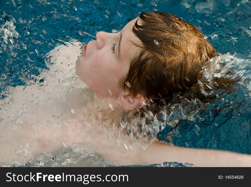 Smiling and happy boy with red hair is swimming and relaxing in a beautiful pool. Smiling and happy boy with red hair is swimming and relaxing in a beautiful pool