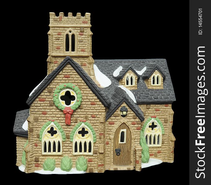 A miniature ceramic church with Christmas decorations and snow around it, isolated on black background. A miniature ceramic church with Christmas decorations and snow around it, isolated on black background.