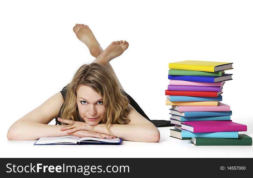 Smiling sweet girl lying on floor reading a book next to stack of colorful books, isolated on white background. Smiling sweet girl lying on floor reading a book next to stack of colorful books, isolated on white background.