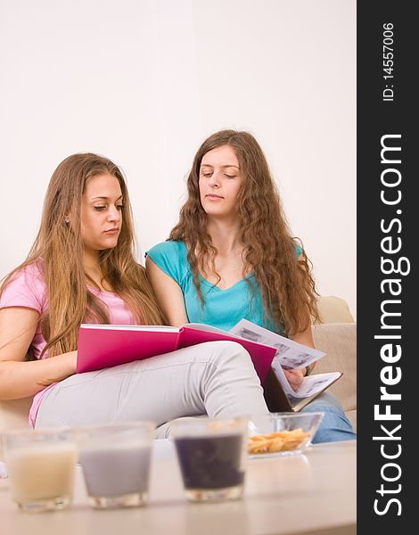 Two young girls sitting in the living room and holding book