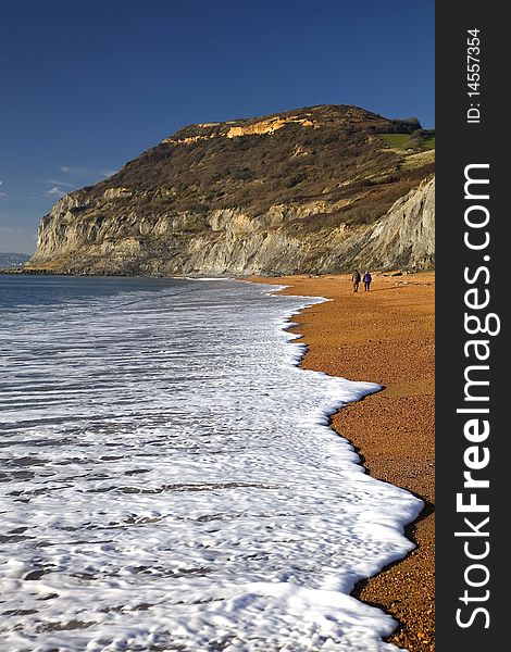 Portrait shot of Golden Cap landmark, west Dorset, England, with couple walking on beach. Portrait shot of Golden Cap landmark, west Dorset, England, with couple walking on beach.