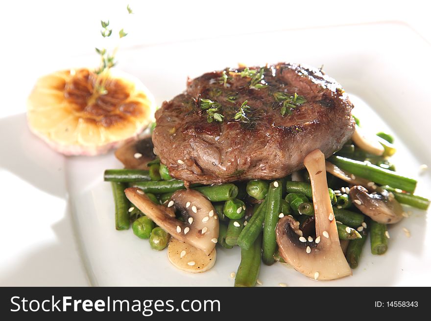 Cooked meat on a plate with sauce and greens