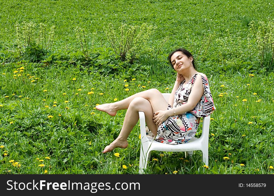 Girl resting in a chair among dandelions