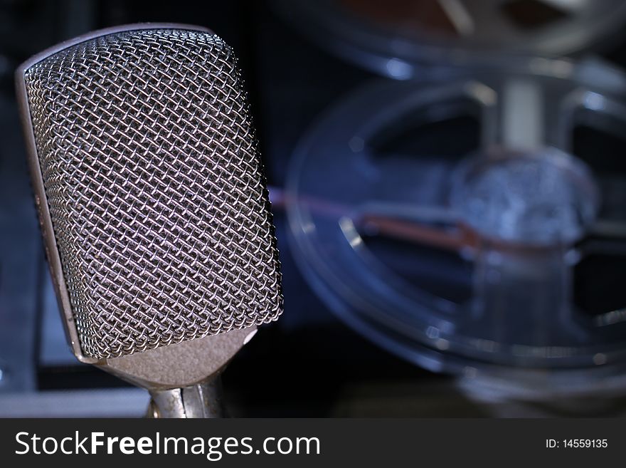 Microphone in focus with reel to reel tape soft focus background. Microphone in focus with reel to reel tape soft focus background.