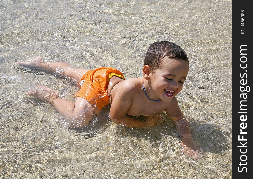 A little boy laughing and joyfully playing in the water at the beach. A little boy laughing and joyfully playing in the water at the beach.