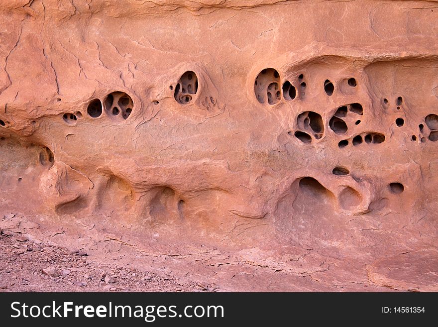 Strange holes eroded into the face of red stone wall in desert of Utah. Strange holes eroded into the face of red stone wall in desert of Utah.