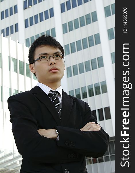 A young Asian businessman standing in front of an office building