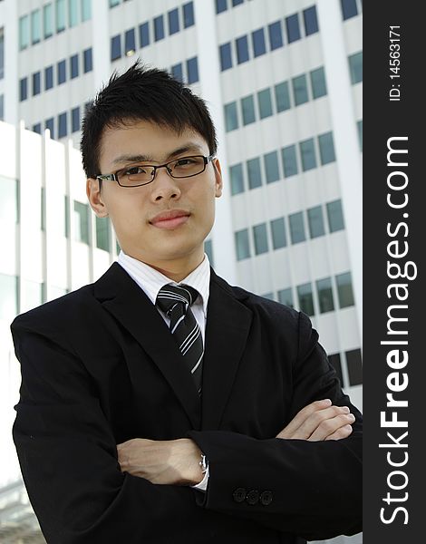 A young Asian businessman standing in front of an office building