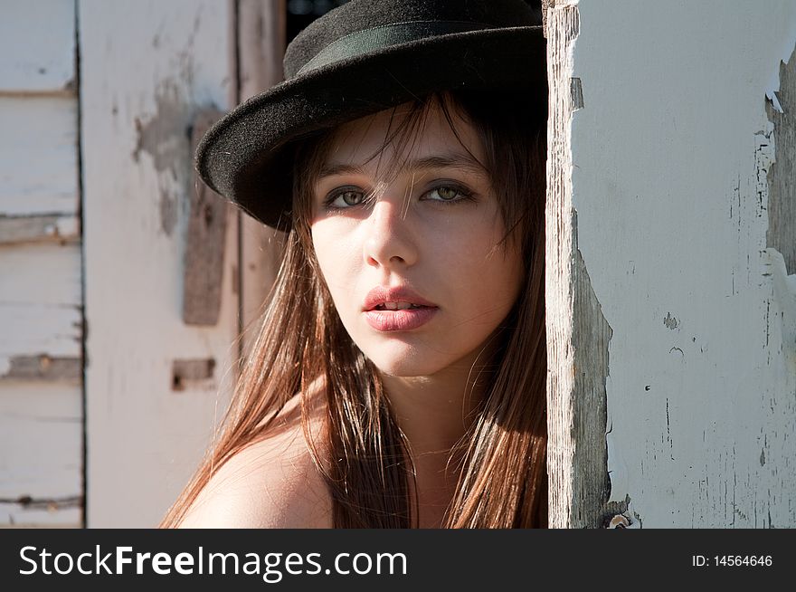 A portrait of a lovely young model wearing a cute hat and standing in a doorway surrounded by peeling white paint. A portrait of a lovely young model wearing a cute hat and standing in a doorway surrounded by peeling white paint