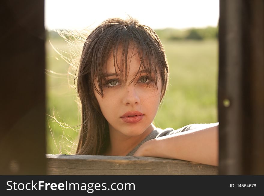 A portrait of a lovely young model standing outside a corrugated tin shed, taken with the photographer standing inside the shed, with walls of the shed framing her face. A portrait of a lovely young model standing outside a corrugated tin shed, taken with the photographer standing inside the shed, with walls of the shed framing her face