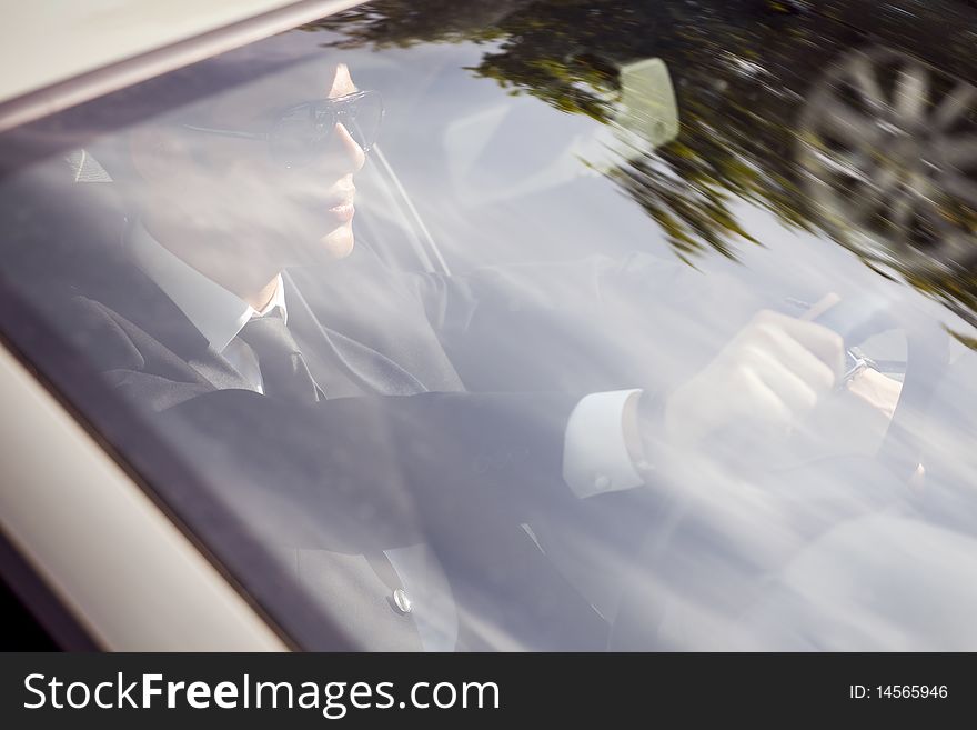 Young businessman in his car at the wheel driving