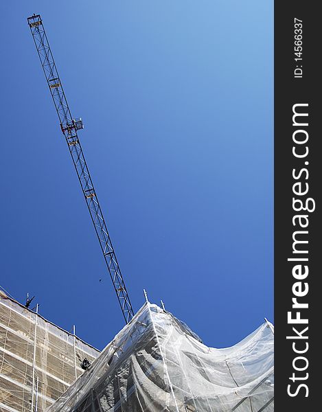 Crane on a construction of a building with blue sky