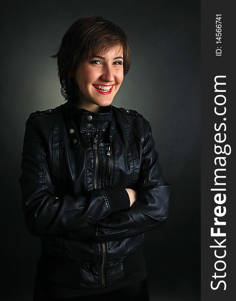 Rock girl in leather outfit smiling on black background