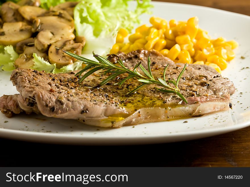 Photo of delicious steak on lettuce bed with mushrooms and mais. Photo of delicious steak on lettuce bed with mushrooms and mais