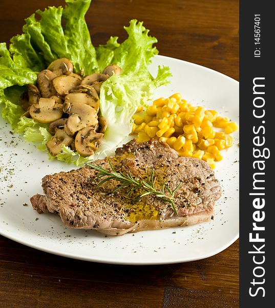 Photo of delicious steak on lettuce bed with mushrooms and mais. Photo of delicious steak on lettuce bed with mushrooms and mais