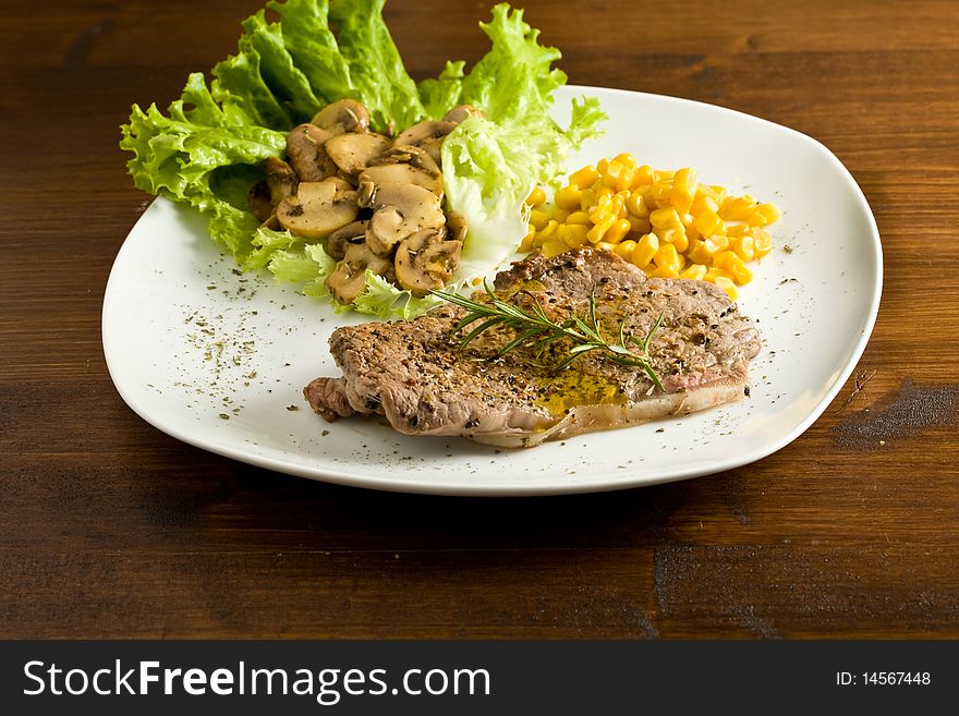 Photo of delicious steak on lettuce bed with mushrooms and mais. Photo of delicious steak on lettuce bed with mushrooms and mais