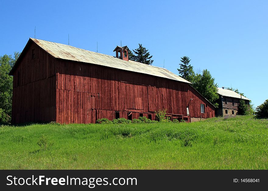 Long red barn with silver roof. Shed addition and another barn at far end. Long red barn with silver roof. Shed addition and another barn at far end.