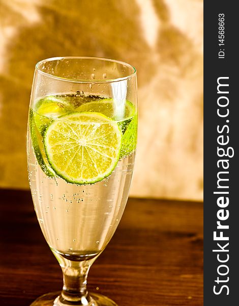 Photo of a yellow lemonade with sparkling bubbles and a lime slicele
